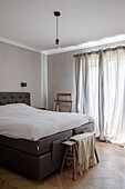 Dark leather bed with headboard and white bed linen