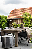 Terrace with rustic wooden table and modern chairs in front of old barn