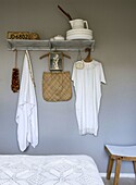 Bedroom area with wall shelf, hooks and white bedspread