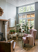 Living area with high windows, wooden floor and indoor plants