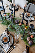 Wooden table set for Christmas with black candles and fir branches