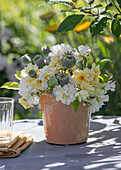 Weisser Blumenstrauß aus Rose (Rosa) 'Christine Helene' und Mohnkapseln (Papaver) auf Terrassentisch