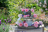 Selbstgebautes Etagere aus Gießkanne mit rosa Rosenblüten