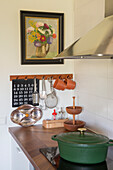 Rural kitchen with calendar, flower painting and green casserole dish