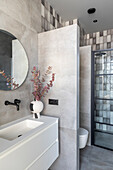 Modern bathroom with round mirror, minimalist washbasin fitting and eucalyptus branches