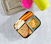 Vegetable sticks with apricot hummus and a sandwich in lunch box