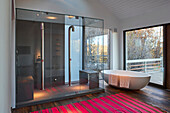 Double shower, bath tub and large window looking out to the deck