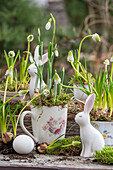 Snowdrops (Galanthus Nivalis), grape hyacinths (Muscari) 'Alba' in ceramic cup and rabbit figurine