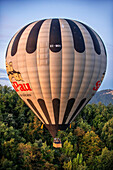 Hot air balloon flying over forest