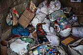 Homeless man sleeping amongst rubbish, Dhaka, Bangladesh