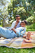 Happy young gay male couple on picnic blanket