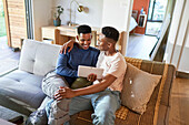 Happy young gay male couple using digital tablet