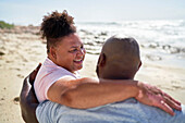Happy gay male couple hugging on beach