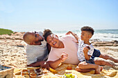 Family laughing and eating on beach