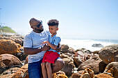 Affectionate father holding son on seaside rocks