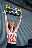 Young woman holding boom box overhead