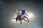 Young friends cheering and gesturing on bean bag chair