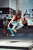 Young woman doing skateboard stunt at skateboard park
