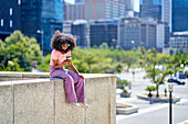 Young woman using smart phone on ledge