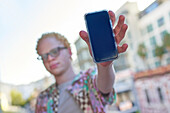 Young man holding smart phone on urban balcony