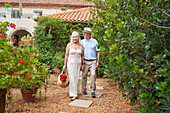 Senior couple with flowers walking in garden