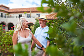 Senior couple walking in garden outside summer villa