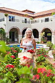 Senior woman picking flowers in villa garden