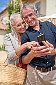Senior couple using smart phone on sunny patio