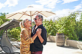 Senior couple laughing and dancing on summer patio