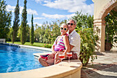 Senior couple relaxing by swimming pool