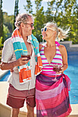 Senior couple drinking cocktails at summer poolside