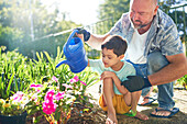 Father and son with Down syndrome watering flowers