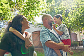 Parents and son with Down syndrome below sunny tree