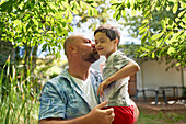 Father kissing son with Down syndrome in summer backyard