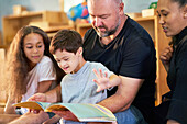 Boy with Down syndrome reading book with family at home