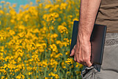 Farmer holding tablet in rapeseed field
