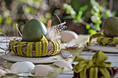 Easter egg in a nest decorated with feathers and eggshells on a garden table