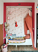 Children's room with flamingo wallpaper and canopy over the alcove bed