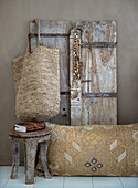 Rustic stool, decorative cushion and jewellery in front of wooden door