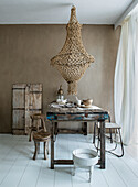 Rustic wooden dining table with macramé chandelier in front of light brown wall