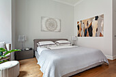 Double bed with geometric bed linen and abstract art