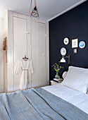 Bedroom with built-in wardrobe and dark blue accent wall, striped bed linen