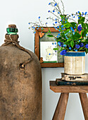 Forget-me-not (Myosotis) in a rustic vase on a wooden table with antique books