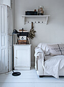 White living room with vintage decor, sofa and hanging shelf