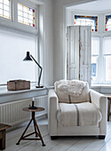 Comfortable reading chair with floor lamp by the window in white living room