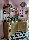 Pink and gold-colored kitchen with checkerboard floor and oriental hanging lamp