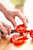 Hands cutting tomatoes