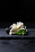 Tête de moine, blackberries and basil on a black serving board