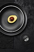 Half an avocado on black plates