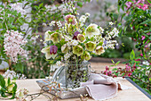 Blumenstrauß aus Felsenbirne (Amelanchier), Schachbrettblume (Fritillaria meleagris), Schlehe, Lenzrose (Helleborus orientalis) in Vase auf Terrassentisch